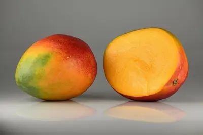 A ripe mango beside one cut in half